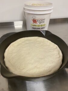 spread the Bucket of Bread dough evenly onto the cast iron pan for pizza
